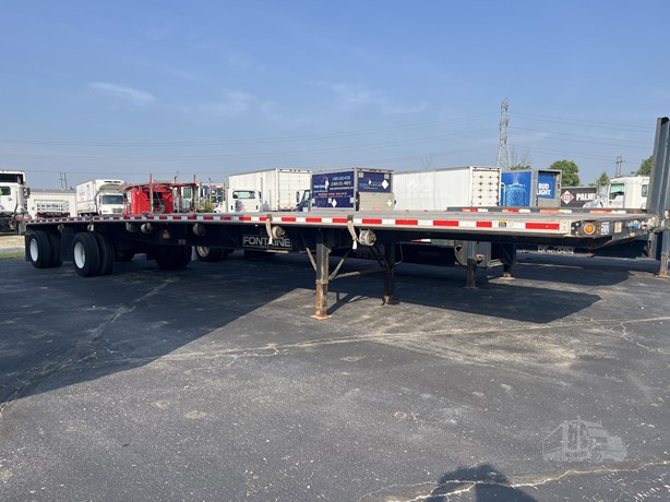 An empty flatbed semi-trailer in a commercial trailer yard
